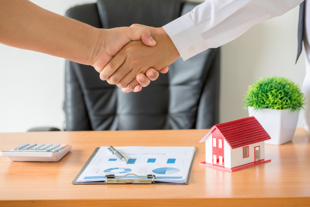 Handen schudden – makelaar en klant schudden elkaar de hand na het ondertekenen van het contract voor de aankoop van een nieuw appartement